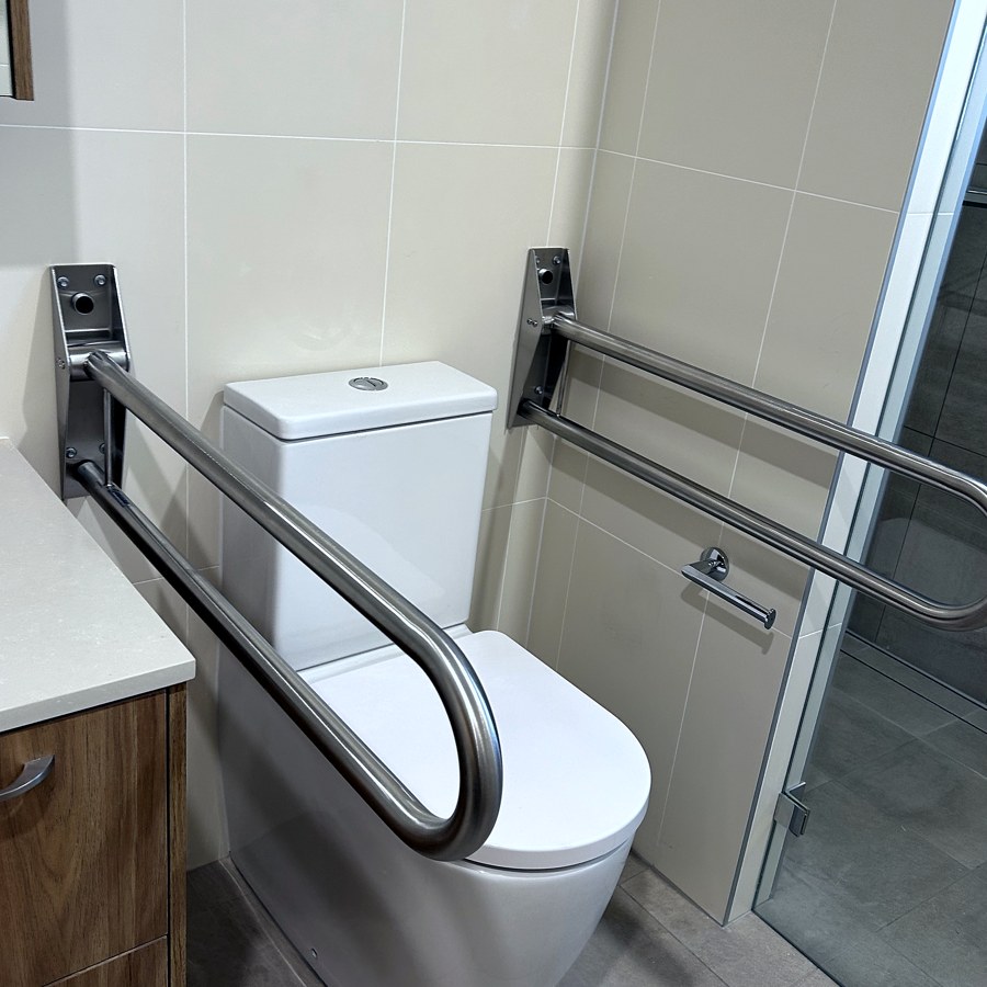 Fold-down and wall-mounted grab rails beside a toilet